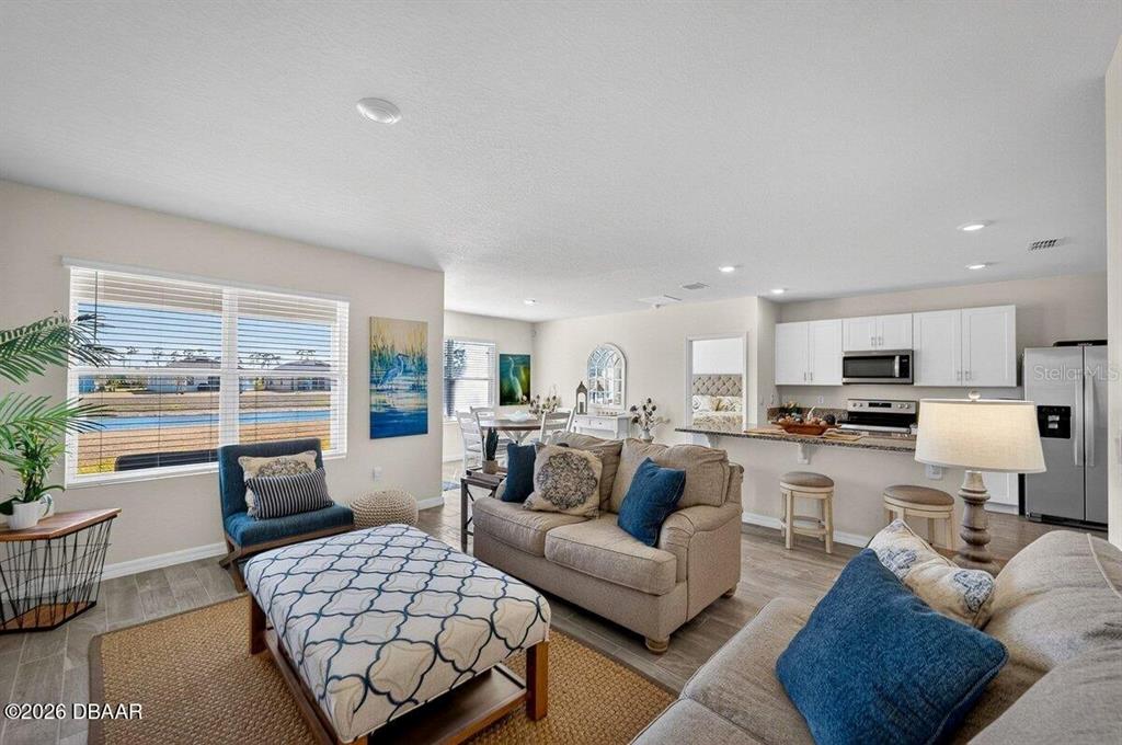 An open-concept living room and kitchen feature neutral walls, wood-look flooring, and a water view — 1346 MIDDLE LAKE DRIVE, ORMOND BEACH, FL