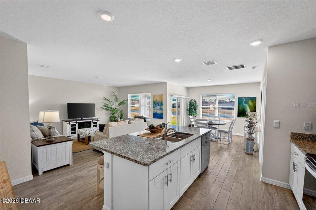 An open-concept kitchen with a granite island overlooks a living area and dining space — 1346 MIDDLE LAKE DRIVE, ORMOND BEACH, FL