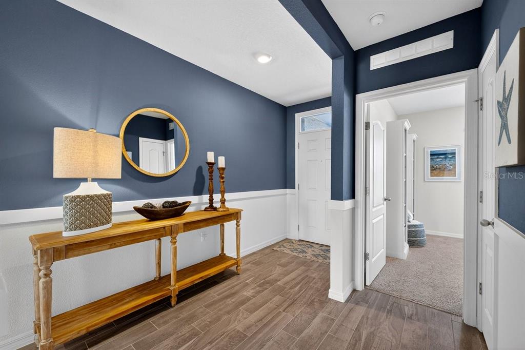 An entryway features a wooden console table, a round mirror, and blue walls with wainscoting — 1346 MIDDLE LAKE DRIVE, ORMOND BEACH, FL