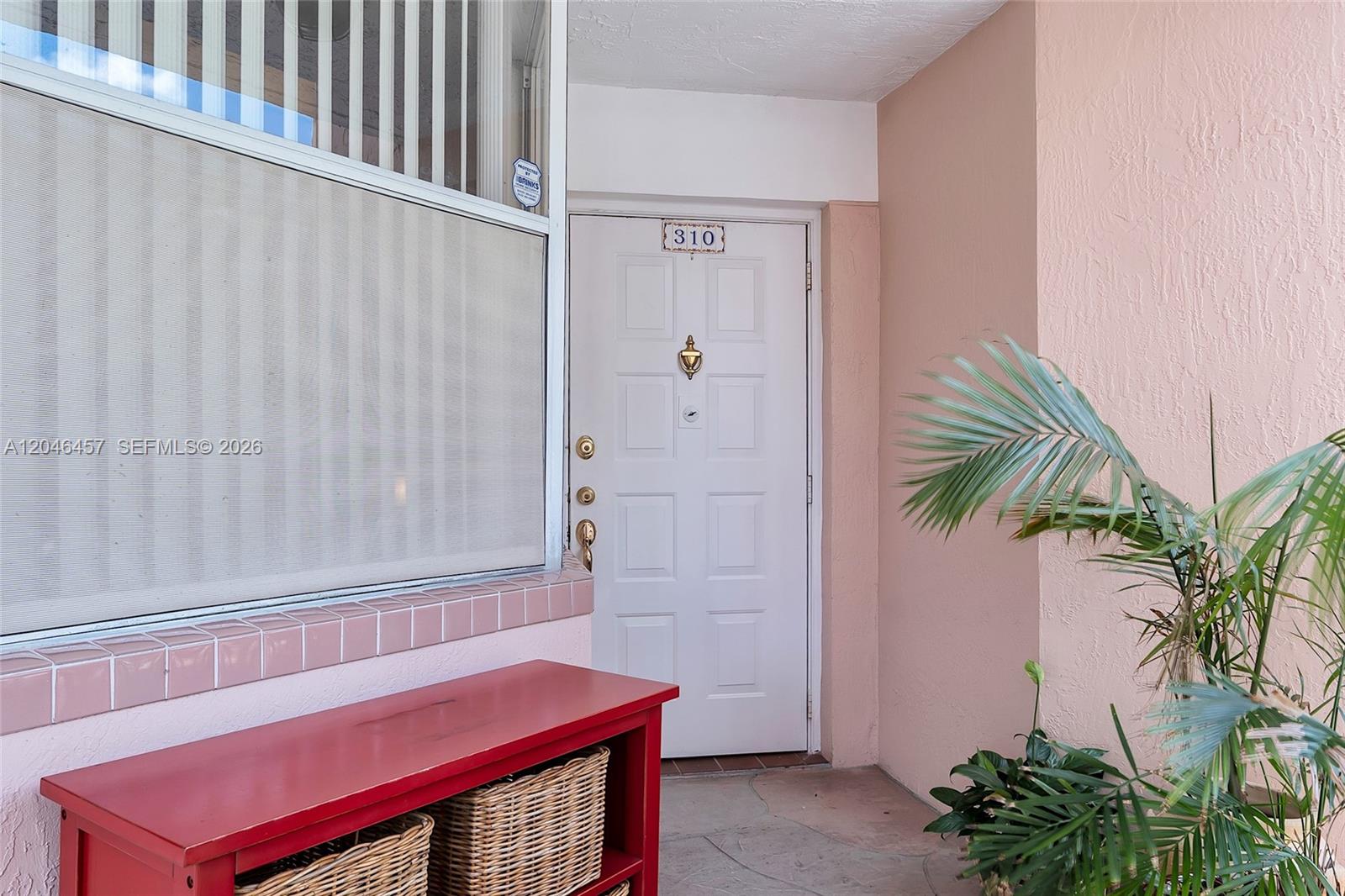 A white front door with a brass knocker sits beside a window and red bench — 2603 NW 103rd Ave # 310, Sunrise FL 33322, SUNRISE, FL