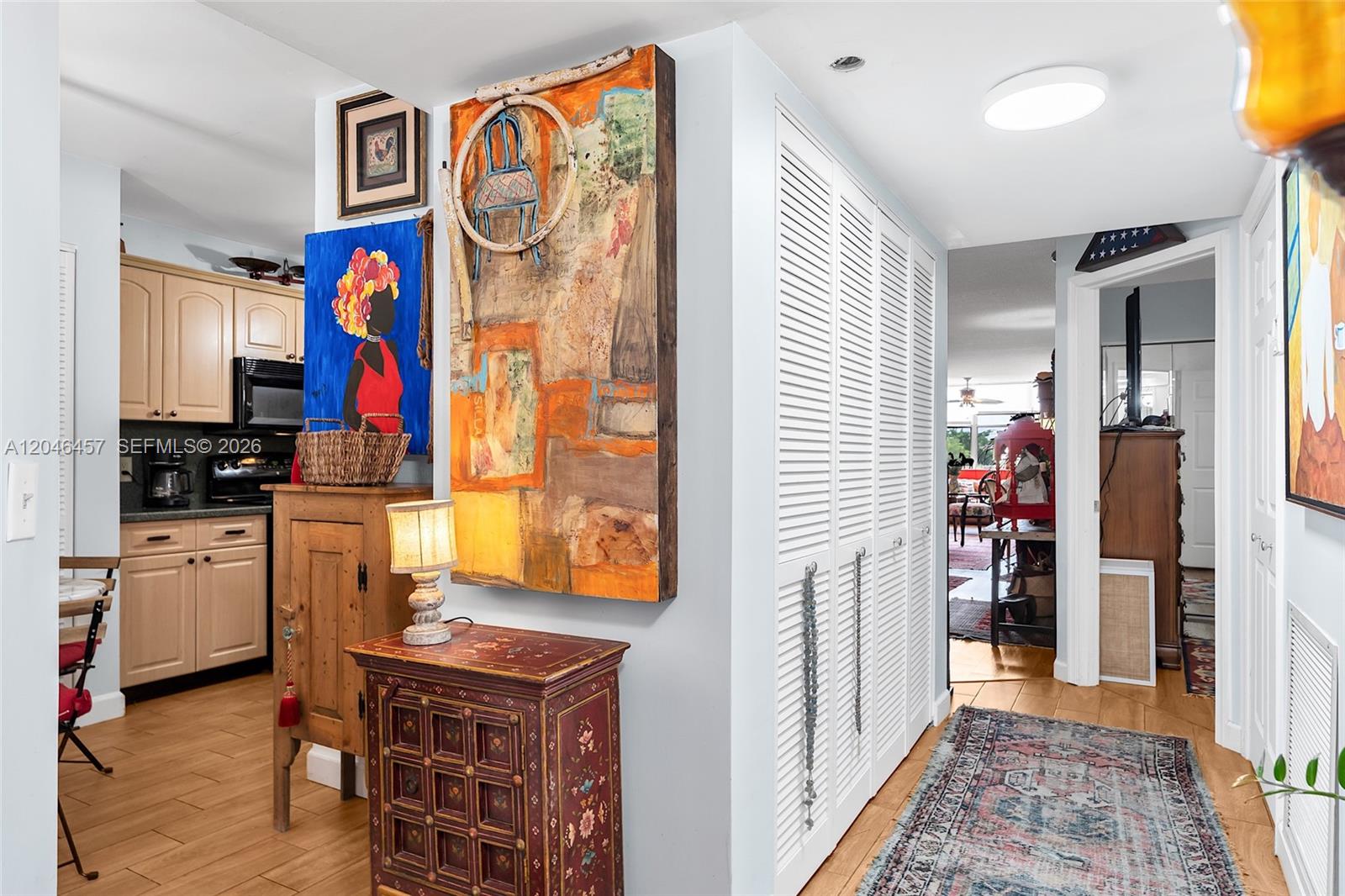 A hallway with a large abstract painting, a small cabinet, and louvered closet doors — 2603 NW 103rd Ave # 310, Sunrise FL 33322, SUNRISE, FL
