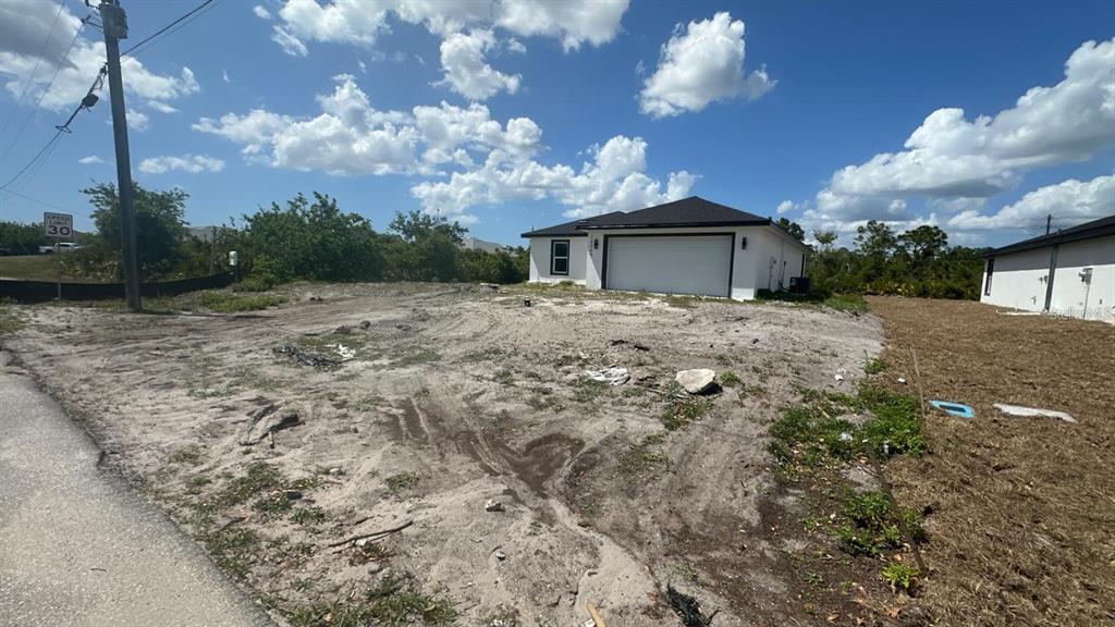A newly constructed white house with a garage sits on a sandy, undeveloped lot — 12266 EDWARDS ROAD, PORT CHARLOTTE, FL