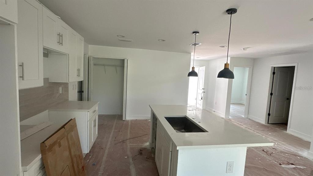 A kitchen features white cabinets, a quartz-topped island with a sink, and pendant lighting — 12266 EDWARDS ROAD, PORT CHARLOTTE, FL