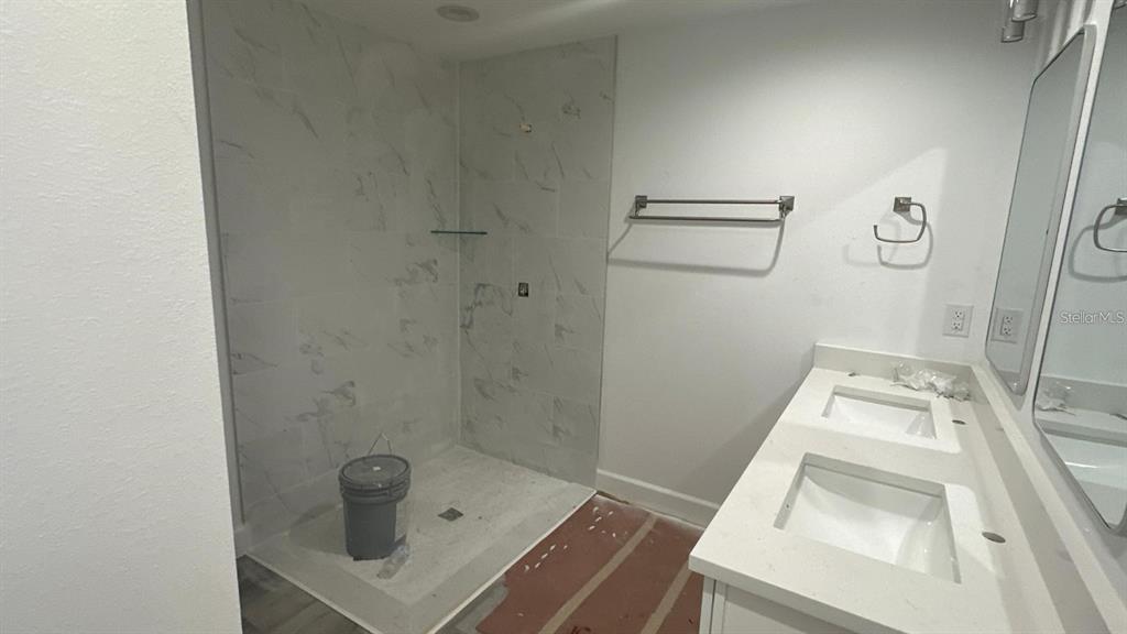 A bathroom features a walk-in shower with marble-look tile and a double-sink vanity — 12266 EDWARDS ROAD, PORT CHARLOTTE, FL