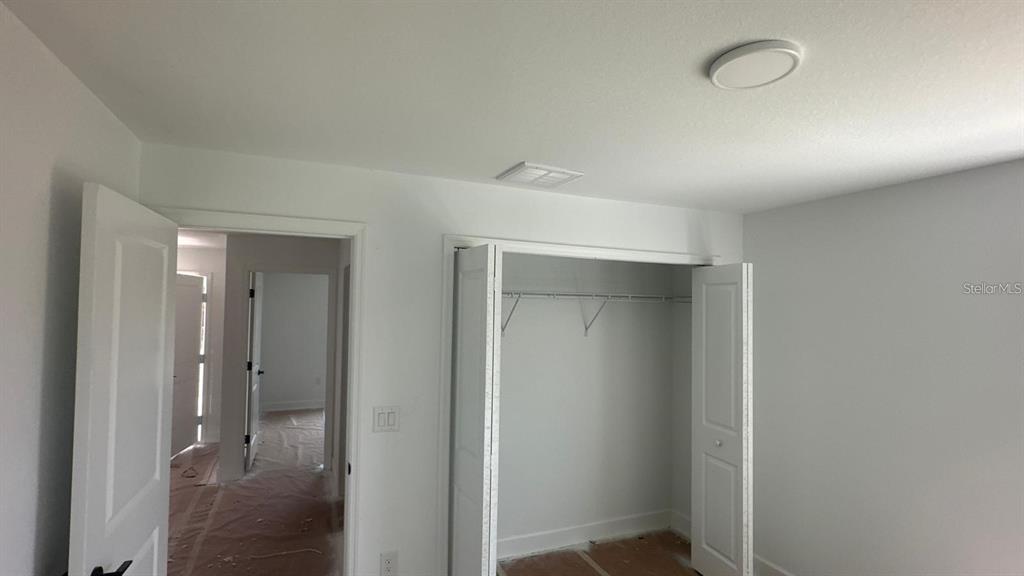 An interior view shows a bedroom with white walls, a closet, and an open doorway — 12266 EDWARDS ROAD, PORT CHARLOTTE, FL