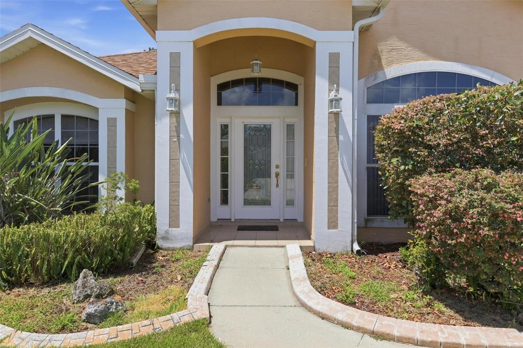 The front entrance of a house features a white door with glass panels and columns — 694 SHAWSBURY WAY, DELTONA, FL