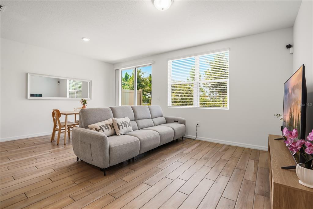 A living room with light wood-look tile flooring, a gray sofa, and a television — 16368 HAPPY EAGLE DRIVE, CLERMONT, FL