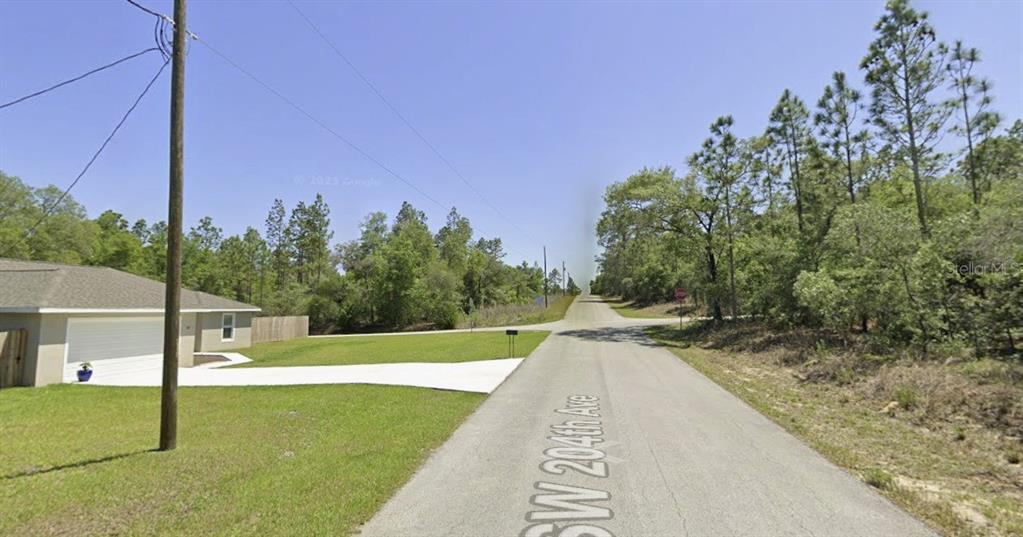 A paved road leads to an intersection surrounded by trees and a residential house — SW 204 TH AVE, DUNNELLON, FL