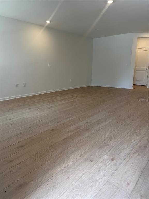 A spacious room with light wood-look flooring, white walls, and recessed ceiling lighting — 5176 CLAY WHALEY ROAD, ST CLOUD, FL