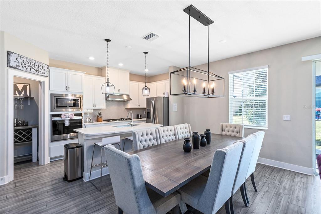 A dining area with a wooden table and upholstered chairs sits adjacent to a modern kitchen — 7962 HAVERHILL WAY, REUNION, FL