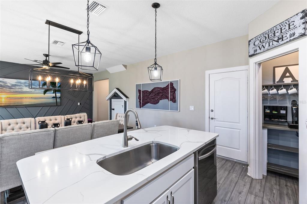 A kitchen island with a stainless steel sink sits before a dining area and pantry — 7962 HAVERHILL WAY, REUNION, FL