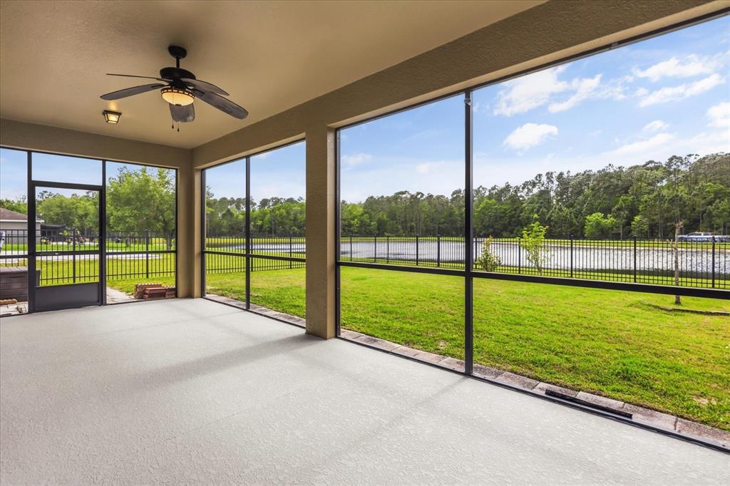 A screened-in patio features a ceiling fan, concrete flooring, and a view of a pond — 10536 CABBAGE TREE LOOP, ORLANDO, FL