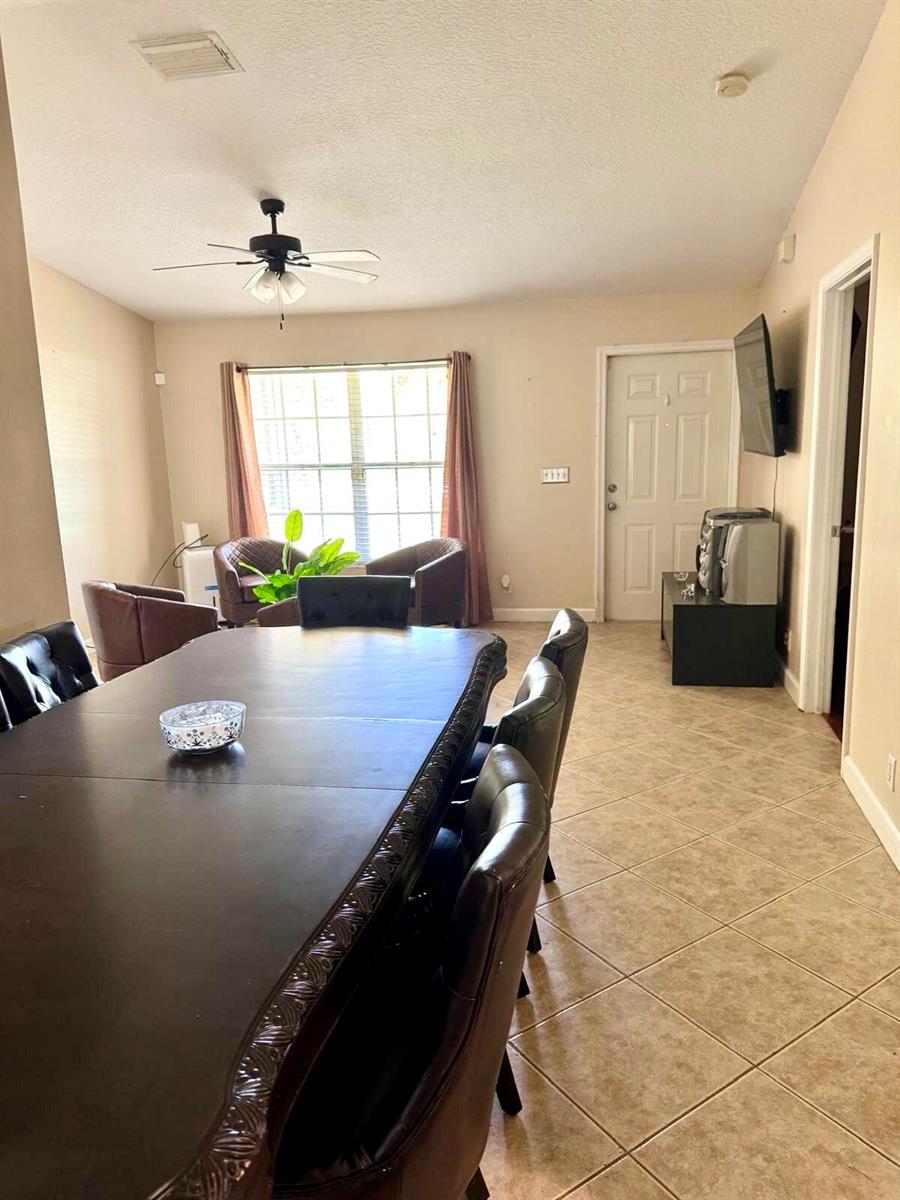 A dining room with a large dark table, leather chairs, tile flooring, and a ceiling fan — 16298 90th Street N, FL 33470, FL