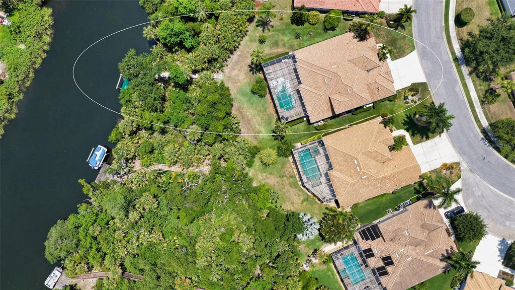 An aerial view shows three waterfront houses with pools and screened lanais along a canal — 6148 PALOMINO CIRCLE, BRADENTON, FL