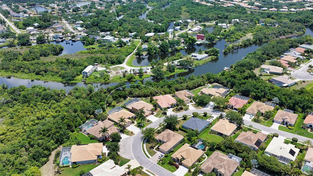 An aerial view shows a suburban neighborhood with houses, swimming pools, and winding waterways — 6148 PALOMINO CIRCLE, BRADENTON, FL