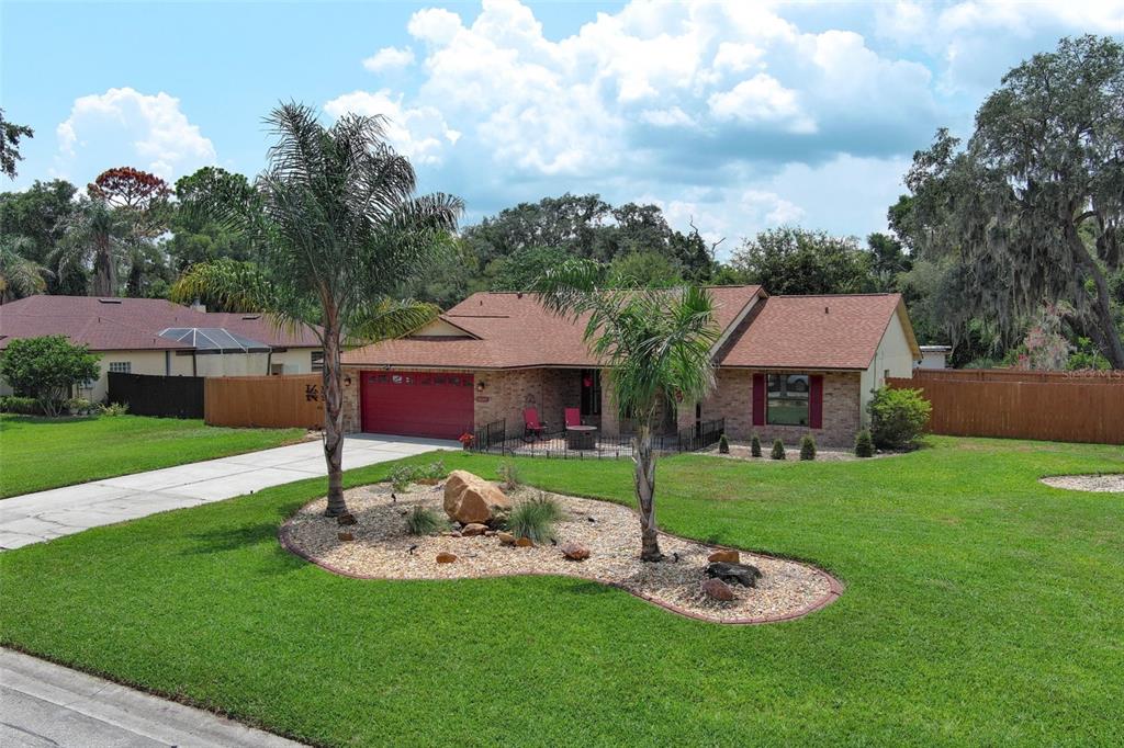 A single-story brick house with a red garage door and two palm trees in front — 35049 SILVER OAK DRIVE, LEESBURG, FL