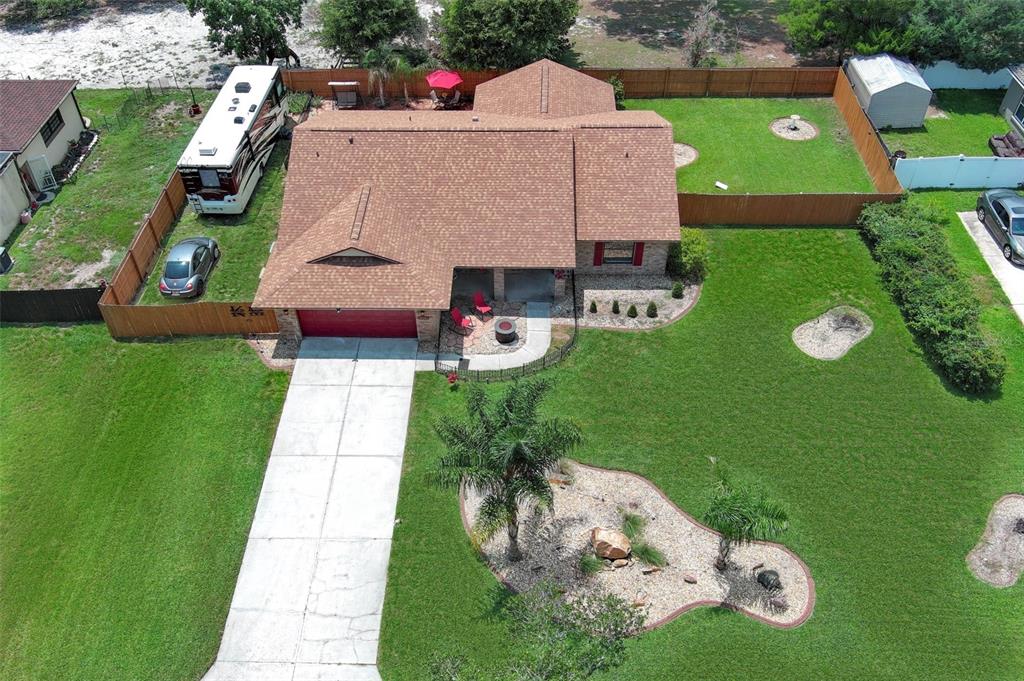 An aerial view shows a single-story house with a brown roof, red garage door, and driveway — 35049 SILVER OAK DRIVE, LEESBURG, FL