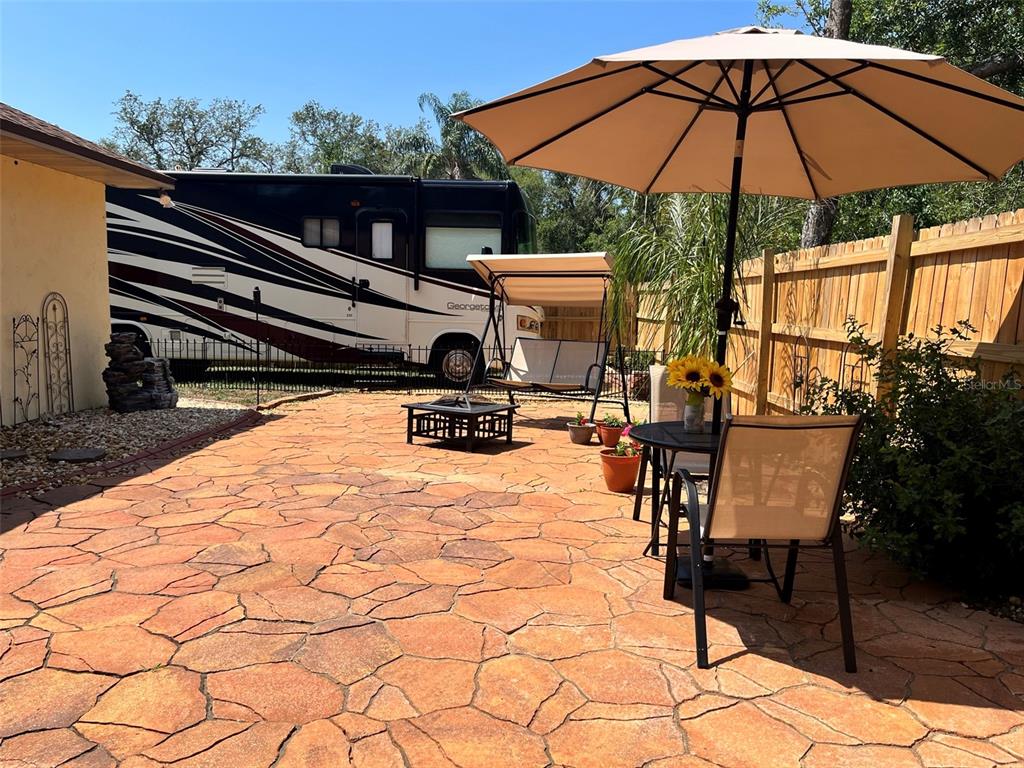 A stone patio features a patio umbrella, a swing, a fire pit, and an RV — 35049 SILVER OAK DRIVE, LEESBURG, FL