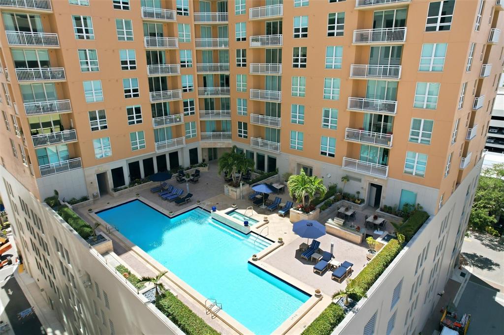 An elevated view of an apartment building courtyard featuring a swimming pool and lounge area — 1350 MAIN STREET UNIT 707, SARASOTA, FL