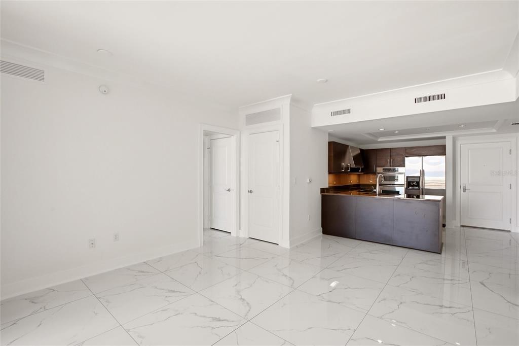 An open-concept living area features white marble-look tile flooring and a kitchen with dark cabinetry — 1350 MAIN STREET UNIT 707, SARASOTA, FL