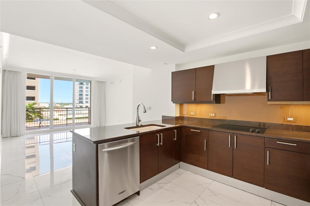 A modern kitchen features dark wood cabinets, stainless steel appliances, and a view of a balcony — 1350 MAIN STREET UNIT 707, SARASOTA, FL