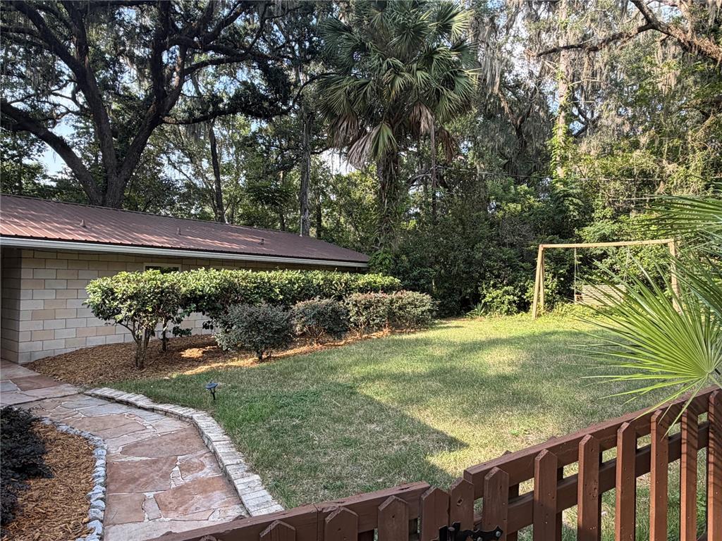 A single-story house with a carport, a wooden fence, and a swing set in the yard — 1732 NW 8TH AVENUE, GAINESVILLE, FL