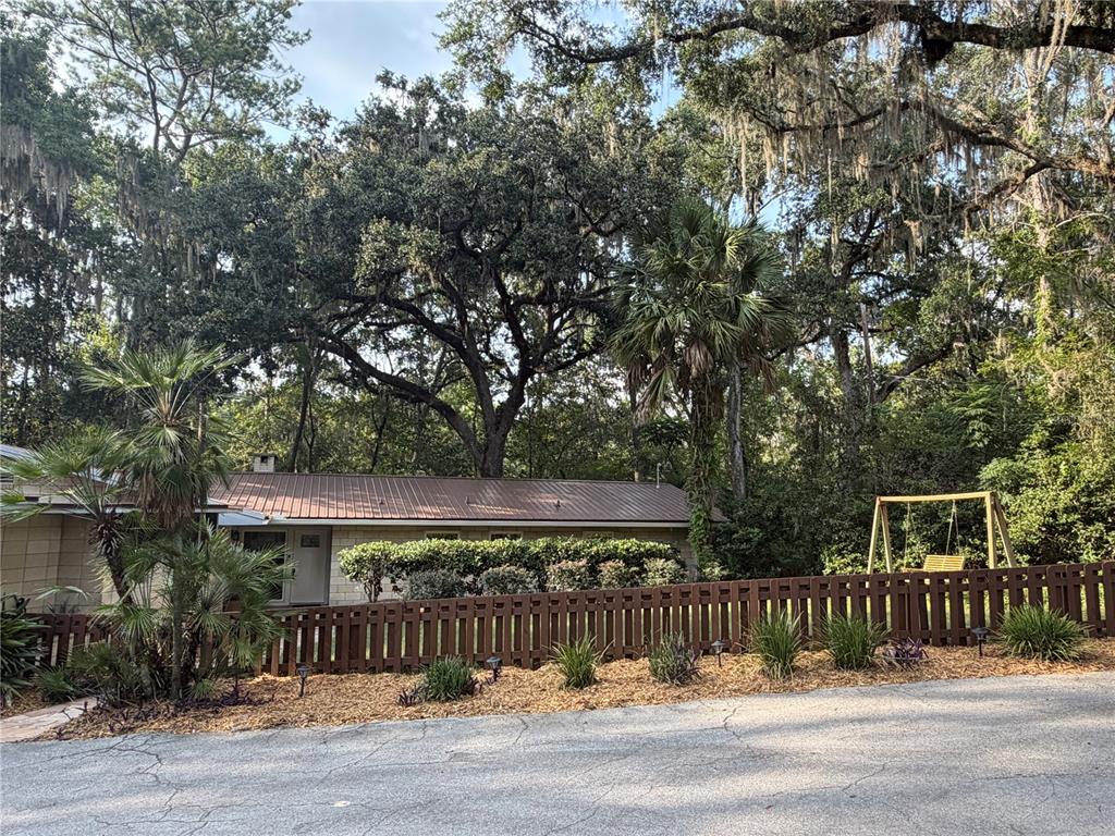 A single-story house with a carport, a wooden fence, and a swing set in the yard — 1732 NW 8TH AVENUE, GAINESVILLE, FL