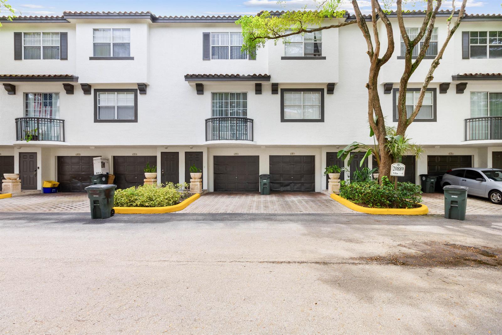 A row of white townhouses features dark garage doors, balconies, and a paved driveway — 20889 Saint Andrews Boulevard, Boca Raton FL 33433, BOCA RATON, FL