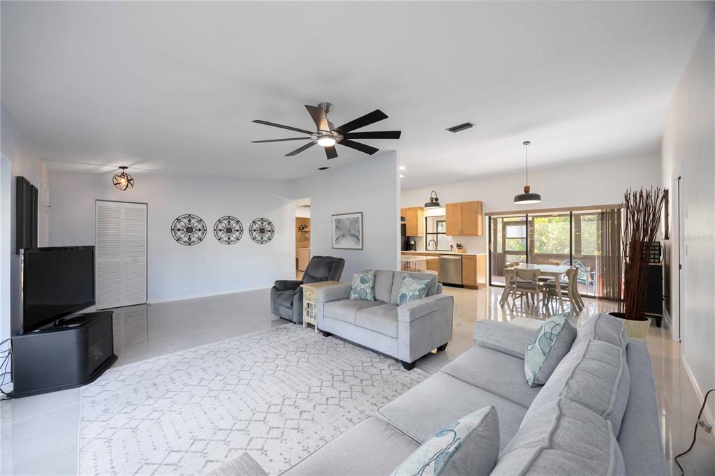 A living room with light gray sofas, a white area rug, and an open kitchen — 17341 HOLMES AVENUE, PORT CHARLOTTE, FL