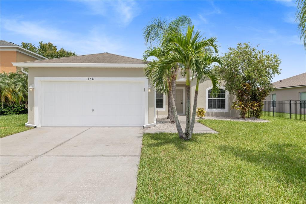 A single-story house with a white garage door, a palm tree, and a grassy lawn — 4611 CABALERRO TRAIL, KISSIMMEE, FL