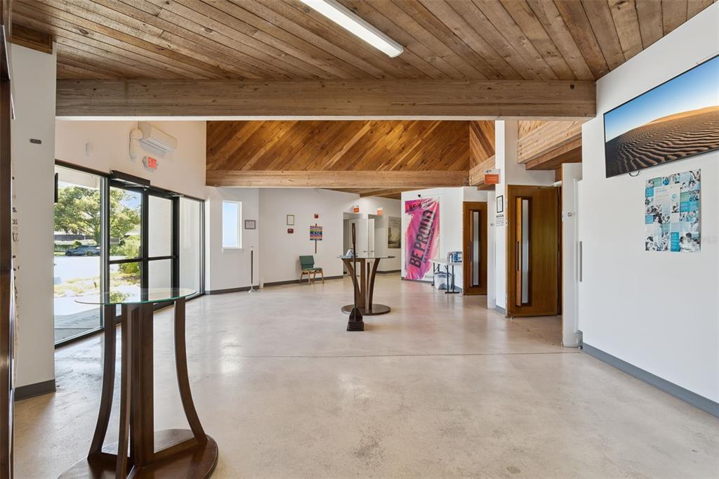 A spacious lobby features a concrete floor, wood-paneled vaulted ceilings, and glass-topped pedestal tables — 9300 UNIVERSITY BOULEVARD, ORLANDO, FL