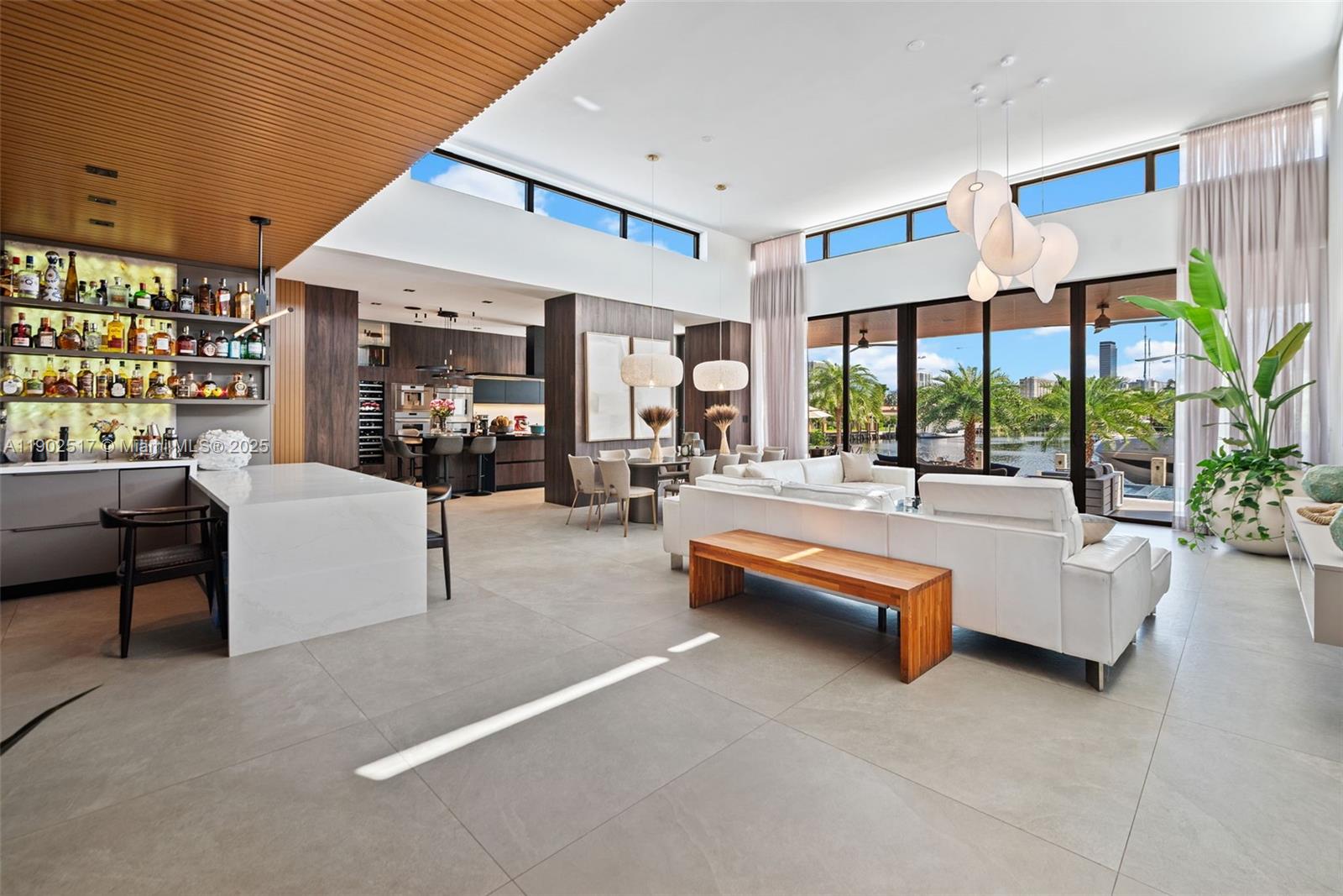 A modern open-concept living area features a bar, dining space, and floor-to-ceiling windows overlooking water — 655 Layne Blvd # 0, Hallandale Beach FL 33009, HALLANDALE BEACH, FL