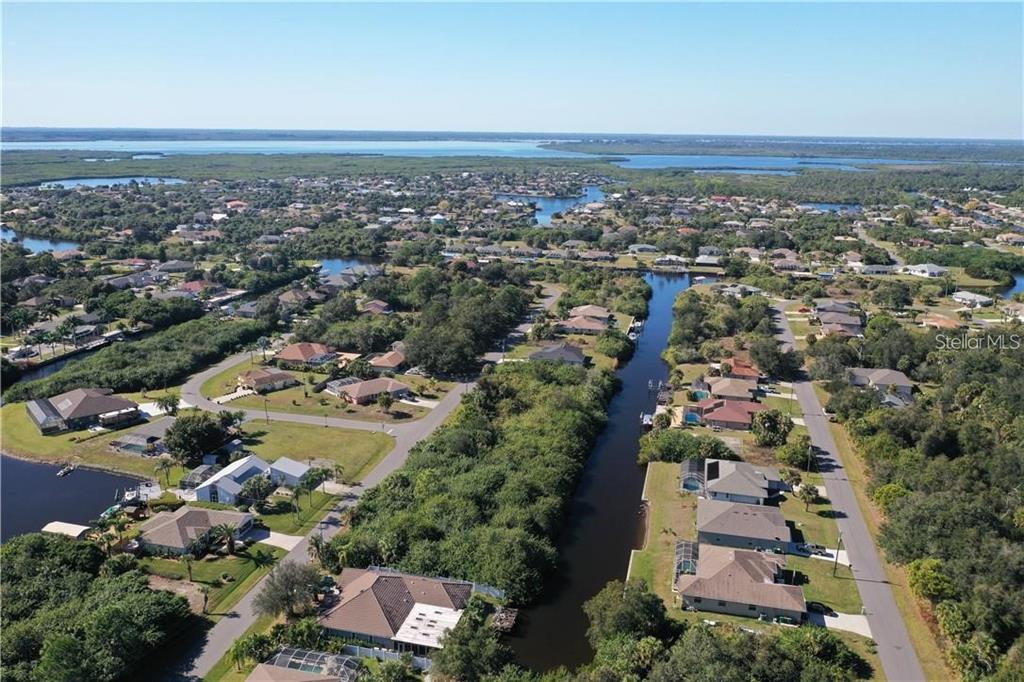 An aerial view shows a residential neighborhood with houses, a canal, and surrounding greenery — 17412 PHEASANT CIRCLE, PORT CHARLOTTE, FL