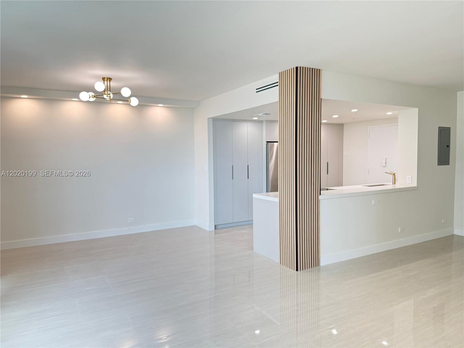 An open-concept living area features light tile flooring, a modern chandelier, and a wood-slatted column — 5055 Collins Ave # 6F, Miami Beach FL 33140, MIAMI BEACH, FL