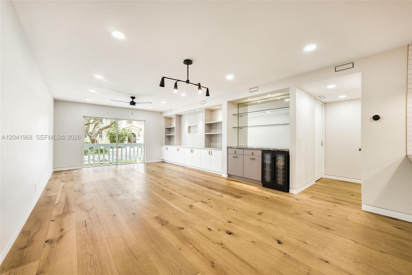 A living room features light wood floors, built-in cabinetry, a wet bar, and sliding doors — 100 Edgewater Dr # 142, Coral Gables FL 33133, CORAL GABLES, FL