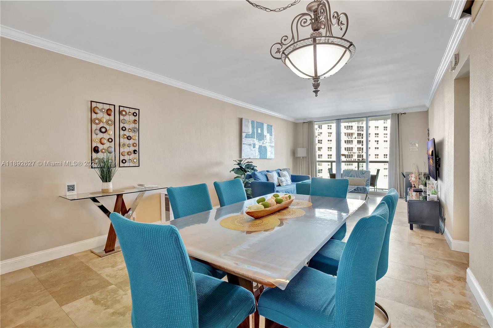 A dining area with a glass table and blue chairs sits before a living room — 3801 S Ocean Dr # 6Z, Hollywood FL 33019, HOLLYWOOD, FL