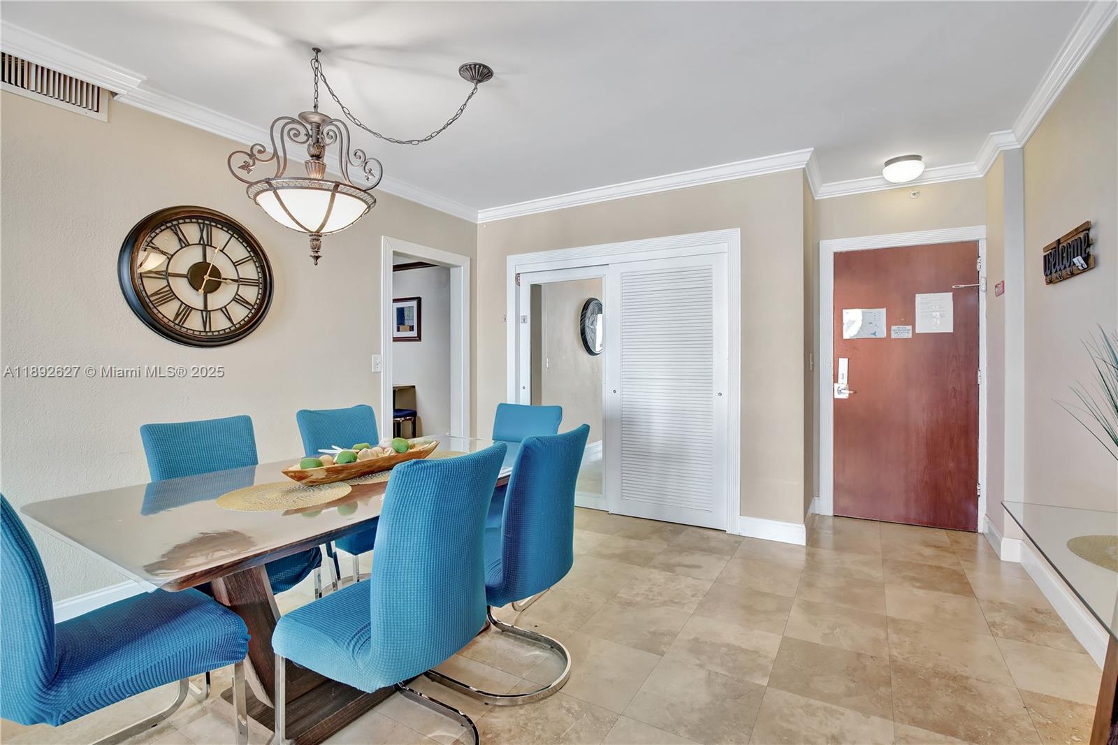 A dining room features a glass-top table, blue chairs, a large wall clock, and tile flooring — 3801 S Ocean Dr # 6Z, Hollywood FL 33019, HOLLYWOOD, FL