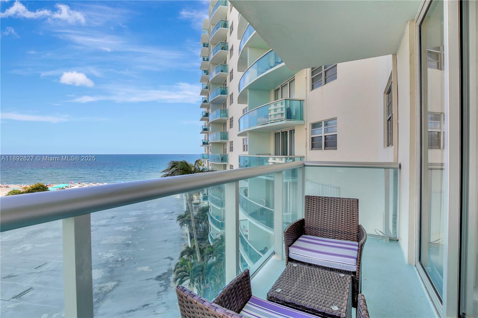 A high-rise balcony features wicker furniture overlooking the ocean and a sandy beach — 3801 S Ocean Dr # 6Z, Hollywood FL 33019, HOLLYWOOD, FL