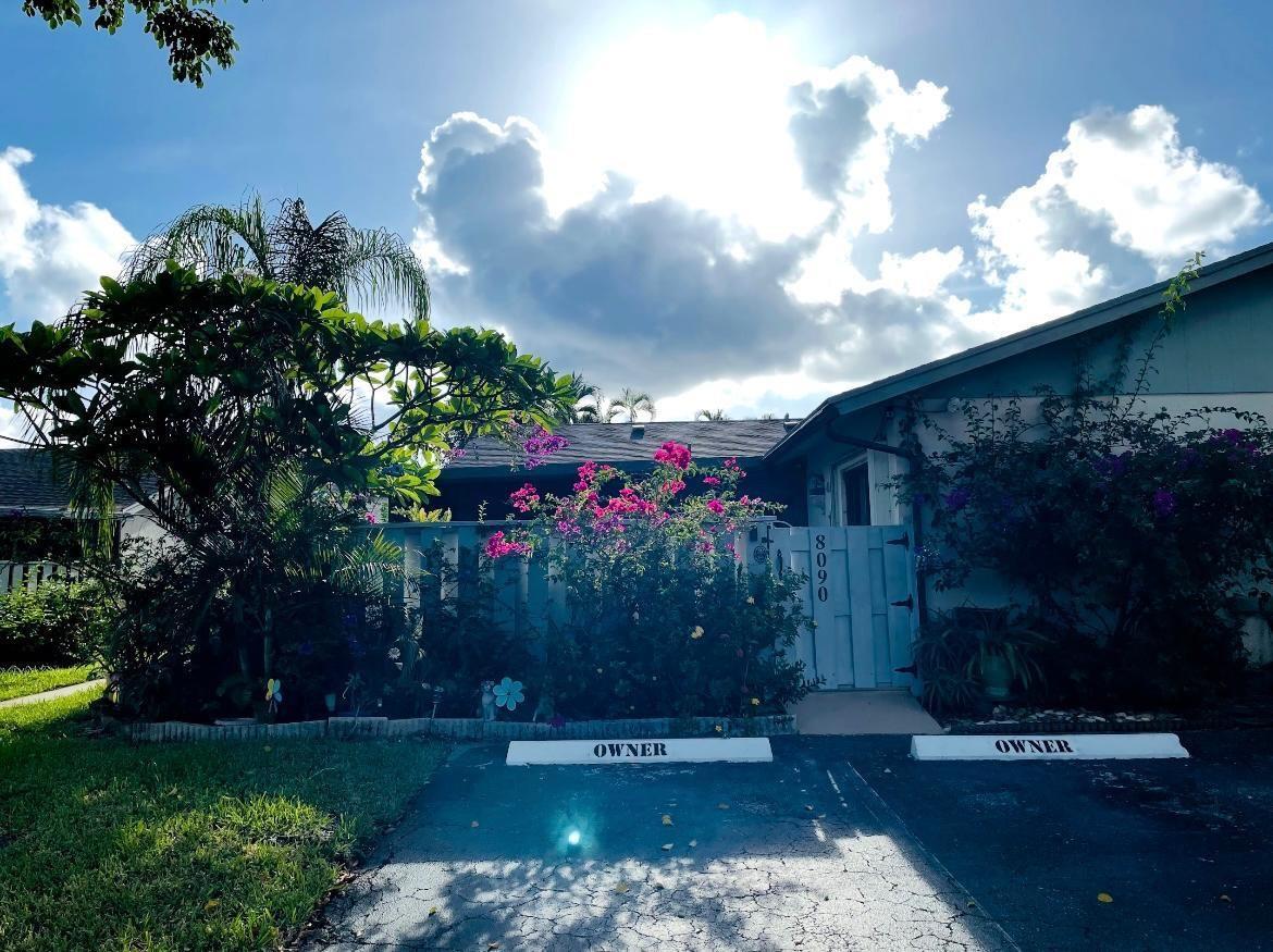 A residential exterior view showing a driveway with two owner-marked parking spaces and a gate — 8090 Ambach Way # B, Hypoluxo FL 33462, HYPOLUXO, FL