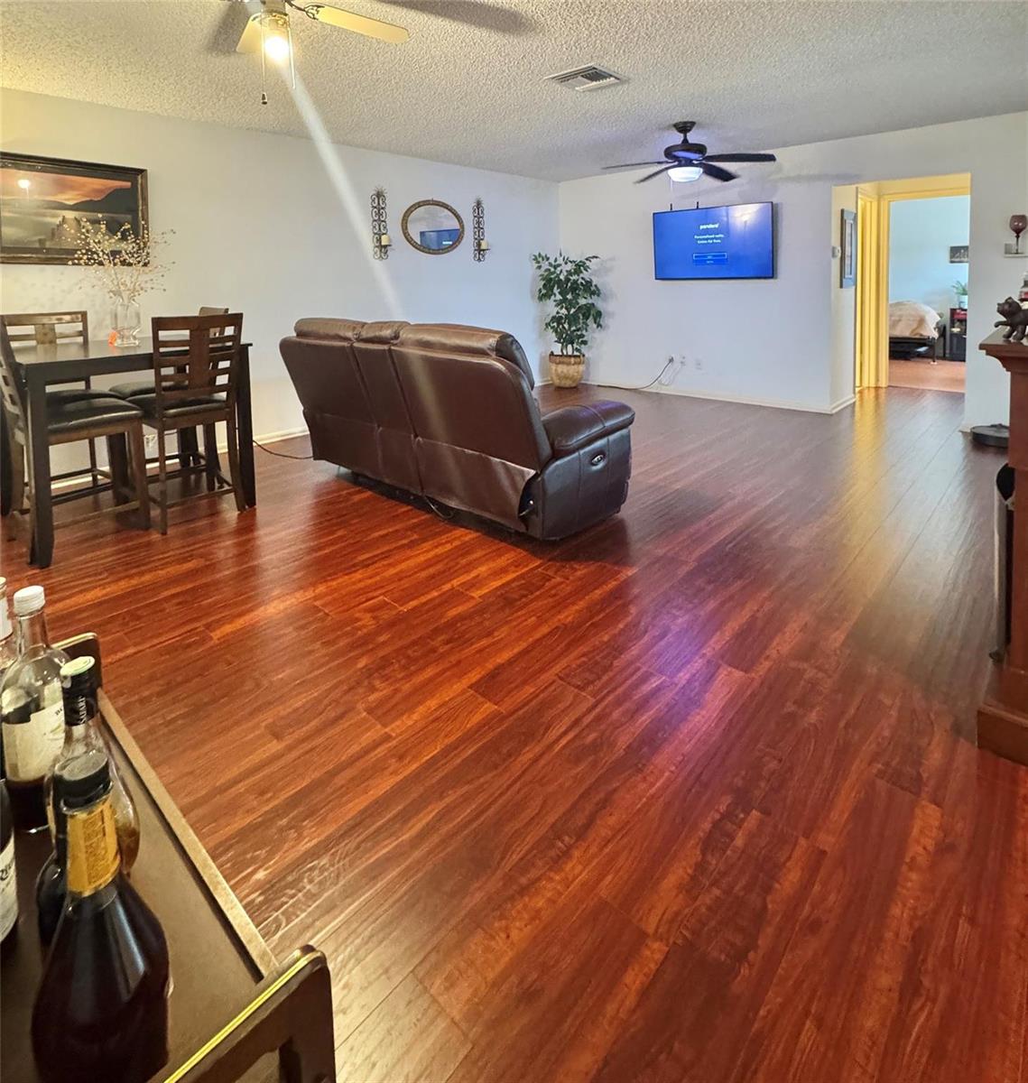 A living and dining area features dark wood flooring, a brown recliner, and a wall-mounted television — 8090 Ambach Way # B, Hypoluxo FL 33462, HYPOLUXO, FL