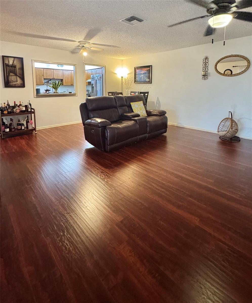 A living room with dark wood flooring, a brown leather loveseat, and a bar cart — 8090 Ambach Way # B, Hypoluxo FL 33462, HYPOLUXO, FL