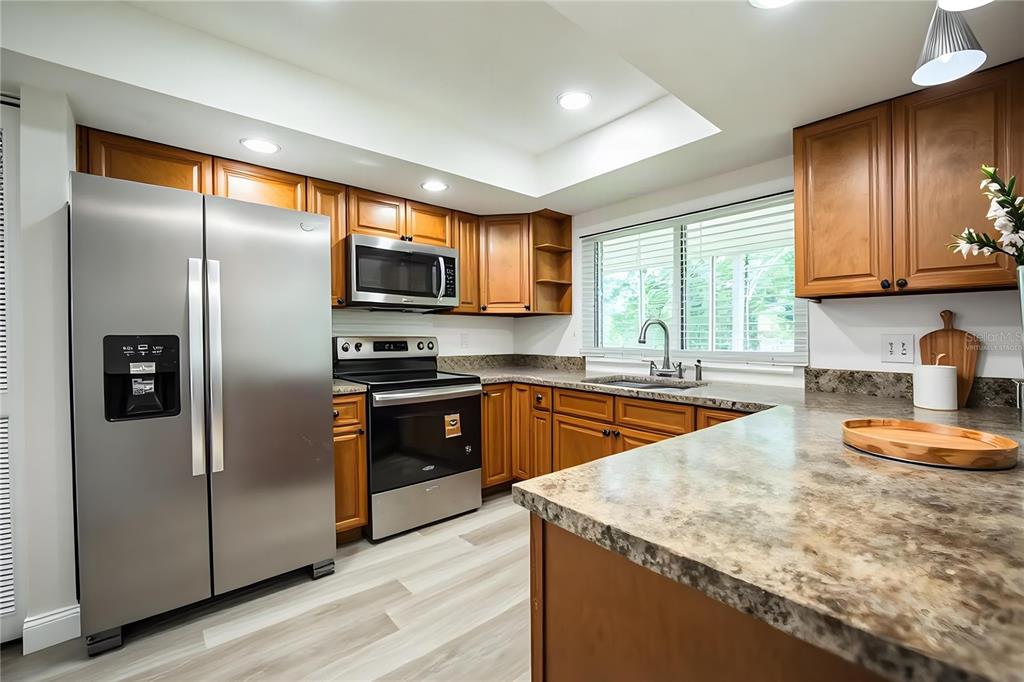 A kitchen features wood cabinets, stainless steel appliances, and a stone-look countertop — 4090 OLD COLONY ROAD, MULBERRY, FL