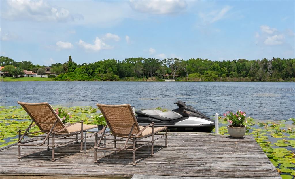 A wooden dock on a lake features two lounge chairs, a jet ski, and potted plants — 1841 LAKE SPIER DRIVE, WINTER PARK, FL