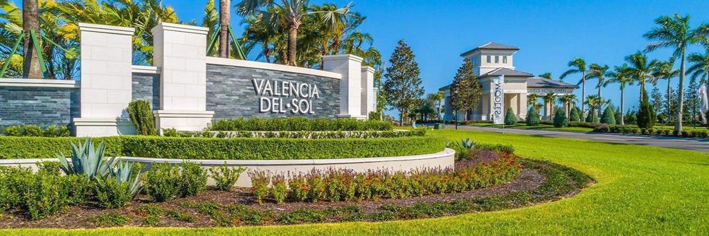 A stone monument sign for Valencia del Sol stands before a landscaped entrance and building — 4838 SEVILLA SHORES DRIVE, WIMAUMA, FL