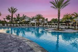 A swimming pool with lounge chairs and palm trees at sunset — 4838 SEVILLA SHORES DRIVE, WIMAUMA, FL