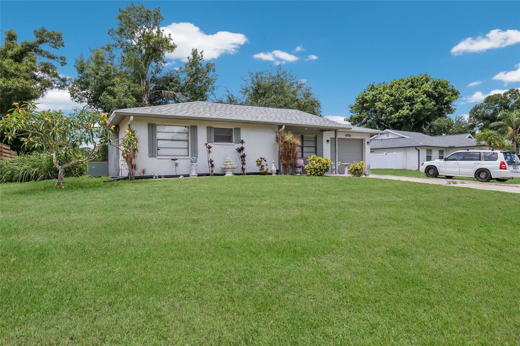 A single-story house with a light-colored exterior, a gray roof, and a large front lawn — 5202 FOXCROFT COURT, SARASOTA, FL