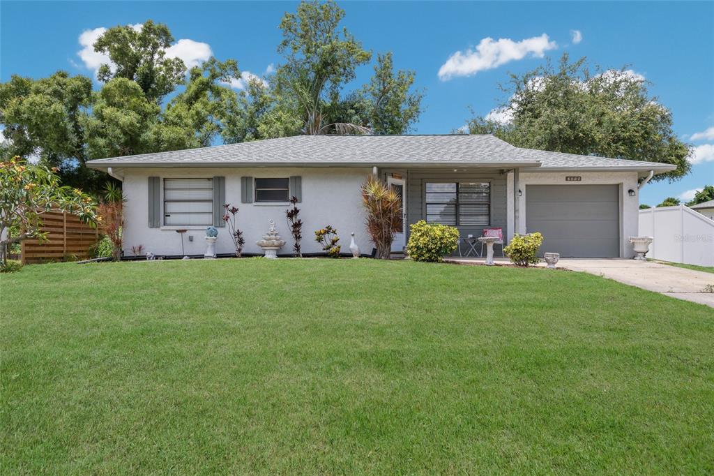 A single-story house with a white stucco exterior, gray roof, and an attached garage — 5202 FOXCROFT COURT, SARASOTA, FL