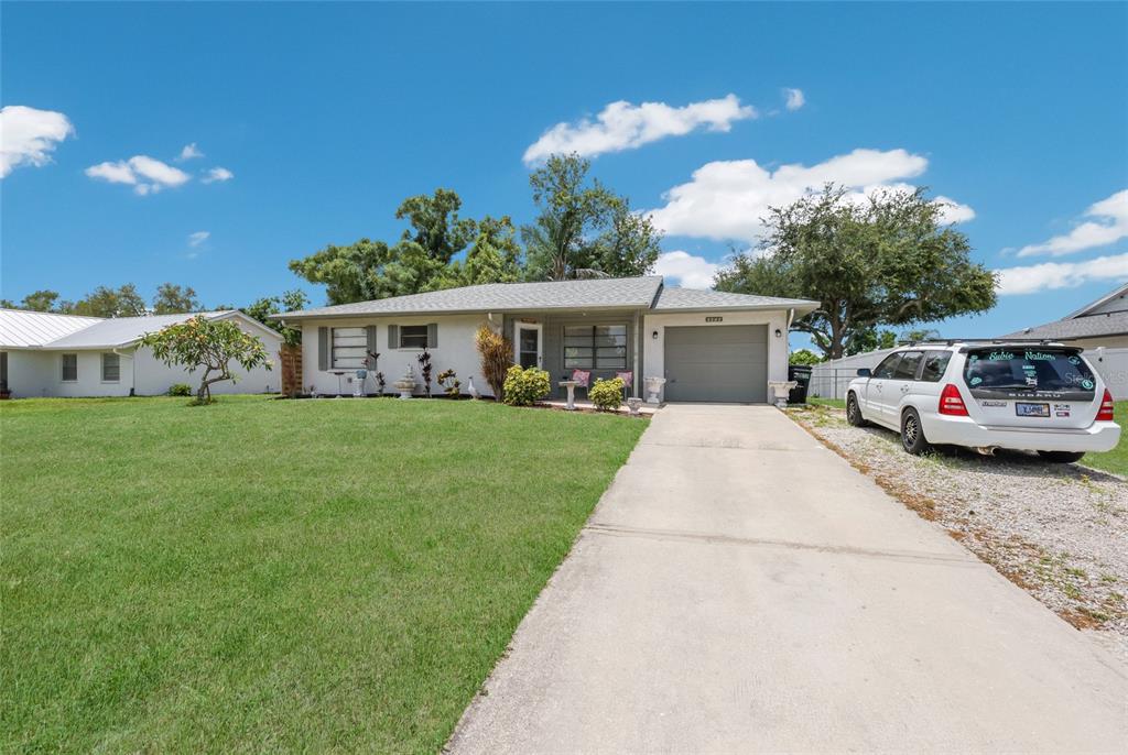 A single-story house with a concrete driveway, a front lawn, and a parked white car — 5202 FOXCROFT COURT, SARASOTA, FL