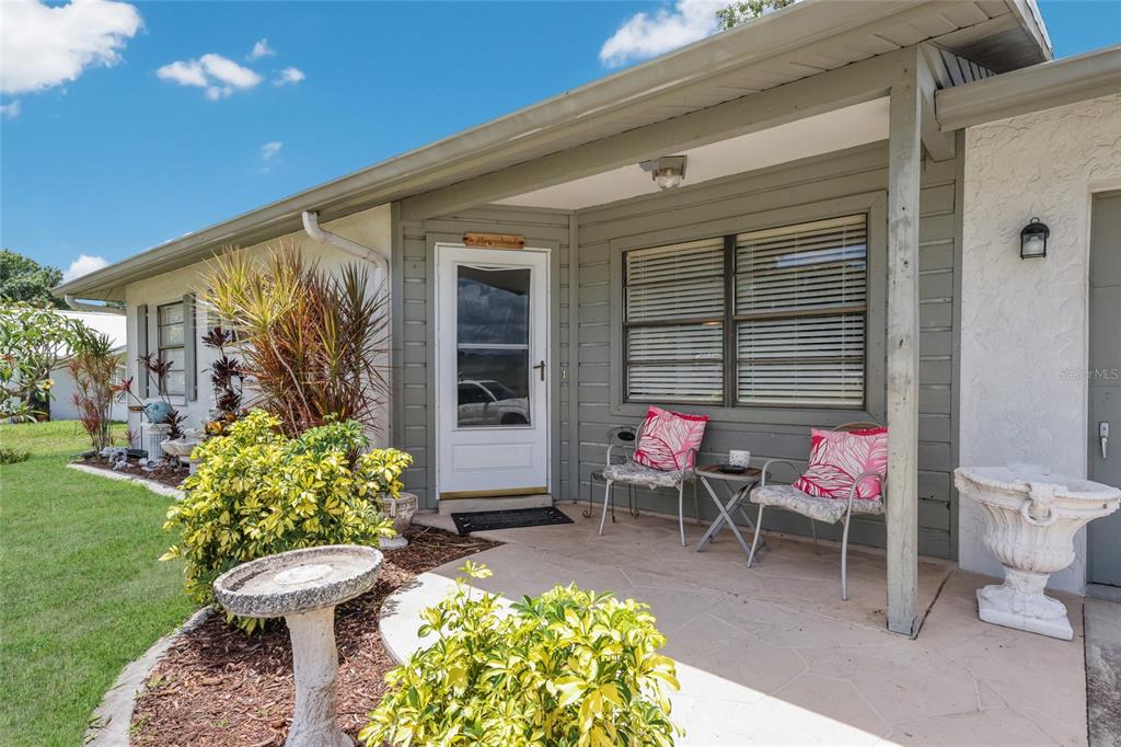 A front porch with a stone patio, two chairs, and a birdbath sits before a house — 5202 FOXCROFT COURT, SARASOTA, FL