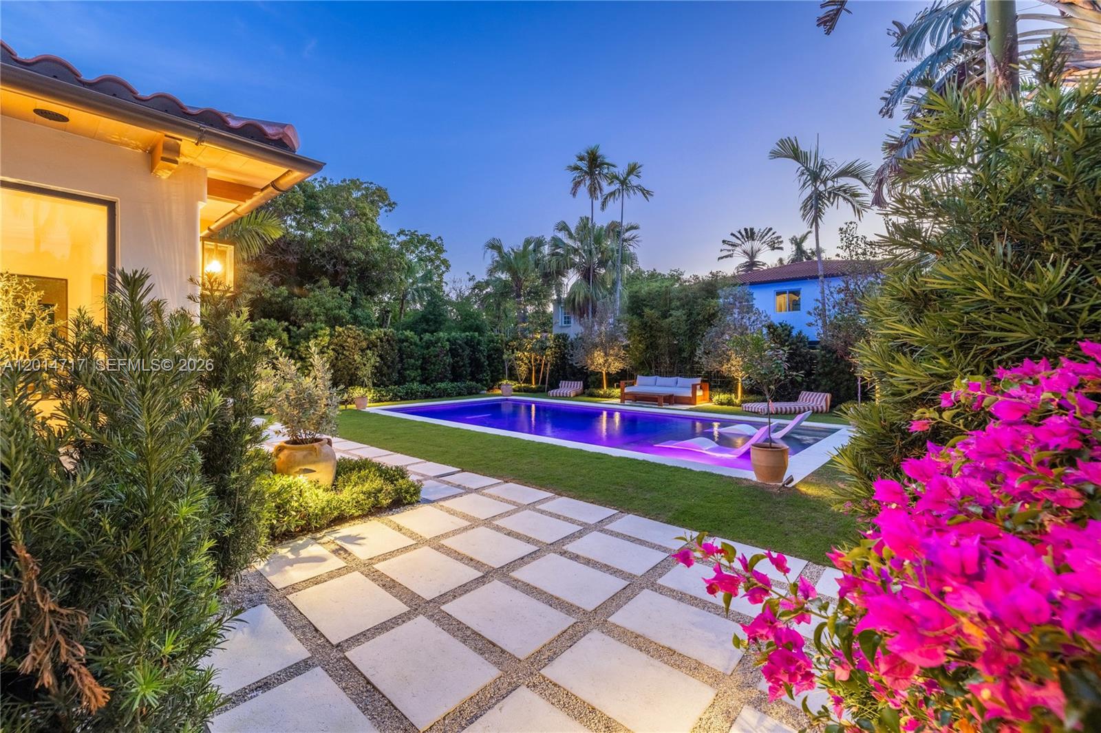 A backyard features a rectangular swimming pool, a stone patio, and vibrant pink bougainvillea — 4430 Royal Palm Ave, Miami Beach FL 33140, MIAMI BEACH, FL